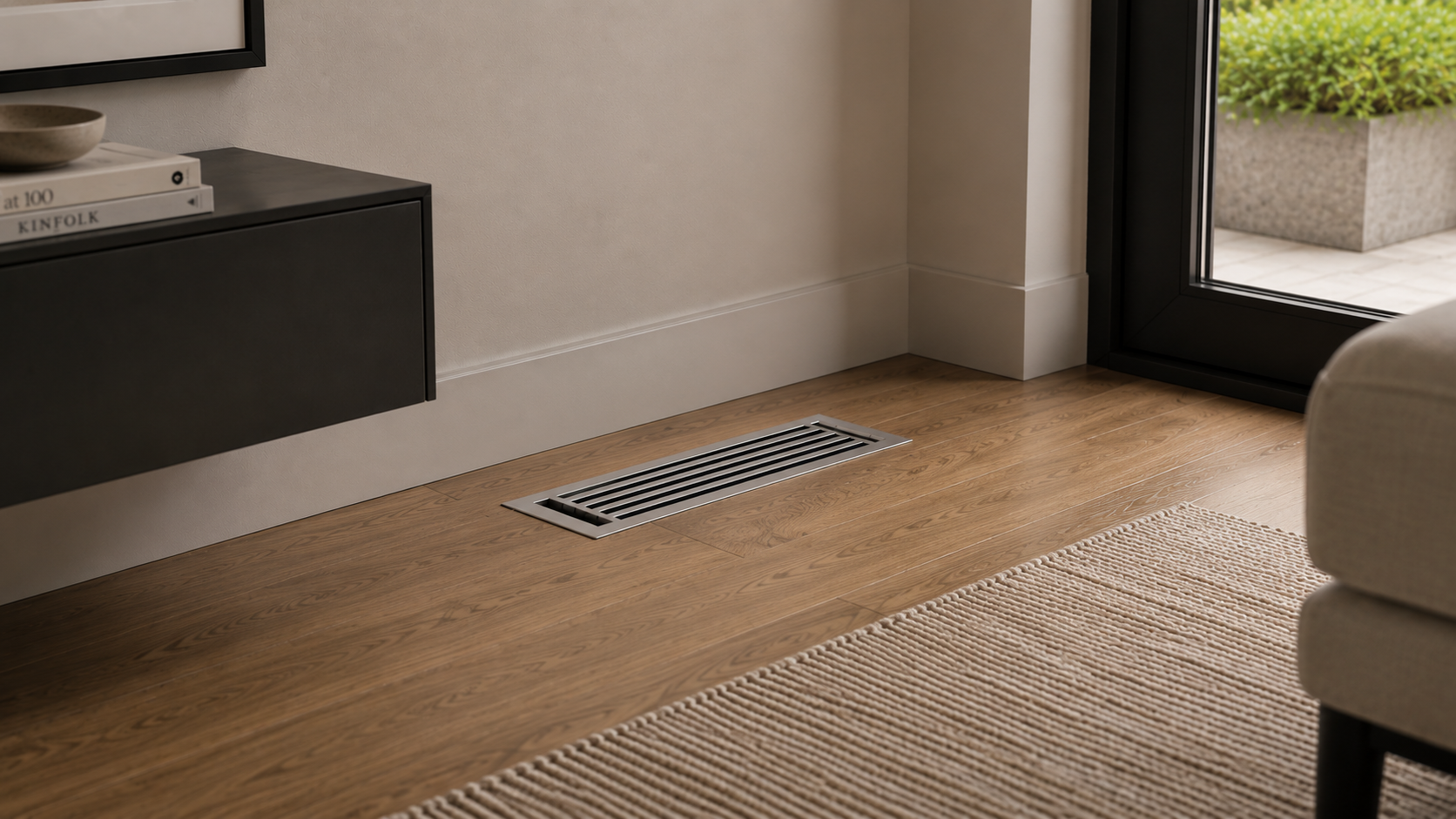 Modern metal floor vent cover installed on hardwood floor near patio door